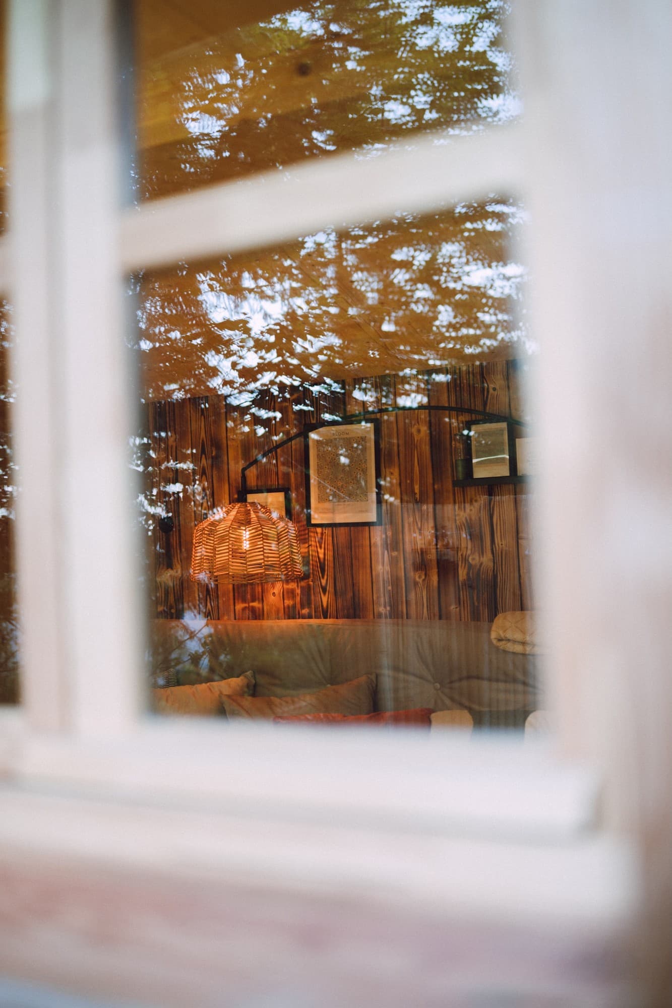 Odraz v okně chatky s lampou